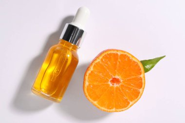 Aromatik mandalina yağı şişede ve turunçgil meyvesi beyaz masada.
