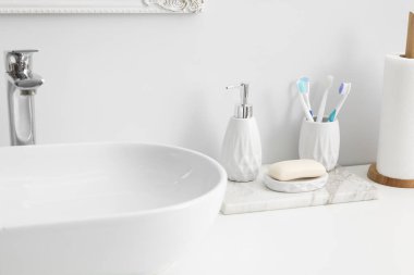 Lavabonun yanında banyo aksesuarları ve kişisel bakım ürünleri var.