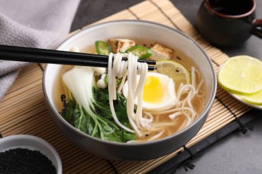 Gri masada yemek çubuklarıyla lezzetli vejetaryen ramen yemek, yakın plan.