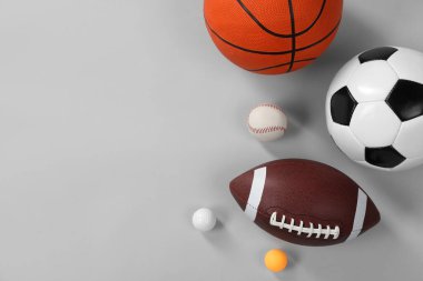 Gri arka planda, düz zeminde birçok farklı spor topu var. Metin için boşluk