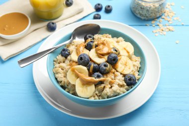 Muz, yabanmersini ve fıstık ezmeli lezzetli yulaf ezmesi açık mavi ahşap masada servis edilir.