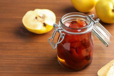 Kavanozda ev yapımı ayva reçeli ve ahşap masada meyveler, yakın plan. Metin için boşluk