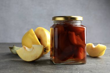 Kavanozda ev yapımı ayva reçeli ve gri desenli masada meyveler. Yakın plan.