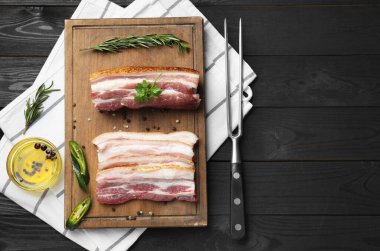 Çiğ domuz eti, kırmızı biber, biber, biberiye ve maydanoz parçaları siyah ahşap masada, düz yatıyordu.