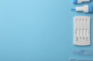 Tek kullanımlık çoklu enfeksiyon ekspres test kiti açık mavi arka planda, düz yatıyordu. Metin için boşluk