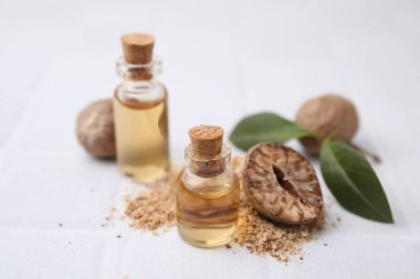 Nutmeg temel yağ ve fındıklar beyaz masada.