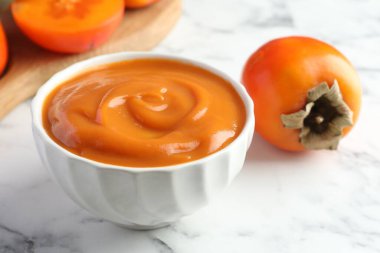 Lezzetli hurma reçeli ve beyaz mermer masada taze meyveler, yakın plan.