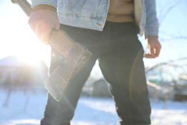 Güneşli kış gününde baltalı bir adam, yakın plan.