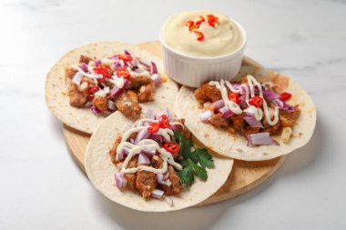 Sebzeli takolar, et ve sos beyaz masada.