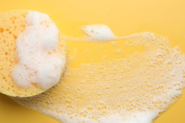 Sarı arka planda köpüklü sünger, üst manzara. Metin için boşluk