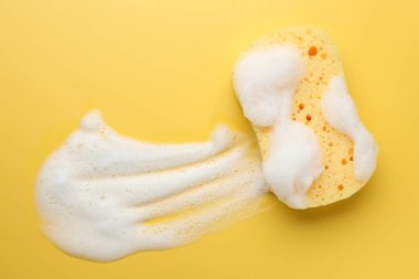 Sarı arka planda köpüklü sünger, üst manzara. Metin için boşluk