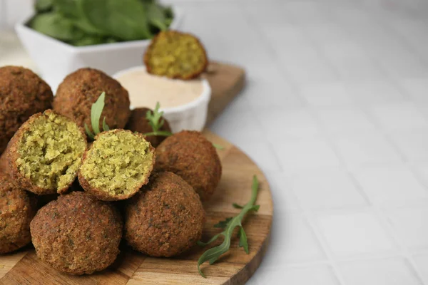 Lezzetli falafel topları ve beyaz fayanslı masada roka, yazı için yer var.