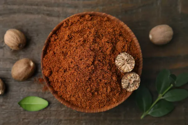 Fındık tozu kasede, tohumlar ve yeşil yapraklar ahşap masada, düz yerde.