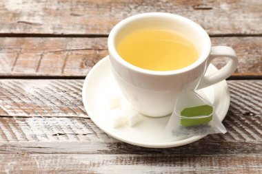 Çay poşetleri ve bir fincan aromatik içecek ahşap kırsal masada, yakın plan. Metin için boşluk