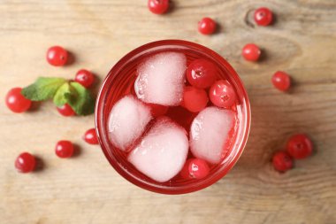 Lezzetli yaban mersini suyu. Bardakta buz küpleri ve ahşap masada taze böğürtlenler.