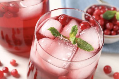 Lezzetli kızılcık suyu, bardakta buz ve beyaz masada taze böğürtlen, yakın plan.