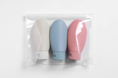 Beyaz arka planda plastik poşet içinde kozmetik seyahat kiti, üst görünüm