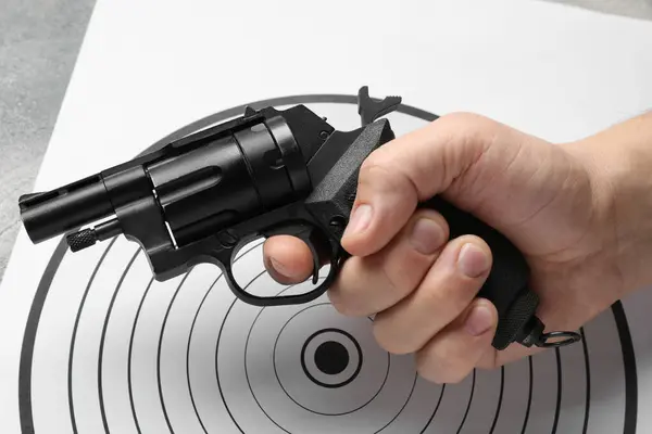 Man with handgun near shooting target, closeup