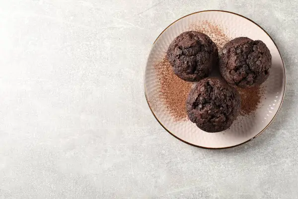 Açık gri masada nefis çikolatalı kekler ve kakao tozu, üst manzara. Metin için boşluk