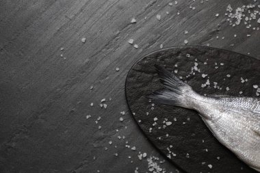 Siyah masada taze çiğ dorado balığı ve deniz tuzu var. Metin için boşluk