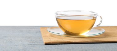 Gri ahşap masada beyaz arka planda yeşil çayı tazeliyor.