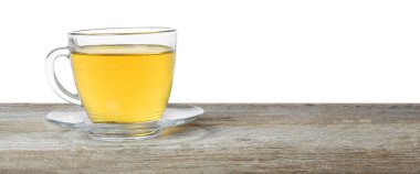 Beyaz arka planda, tahta masada fincanda yeşil çay tazeleniyor.