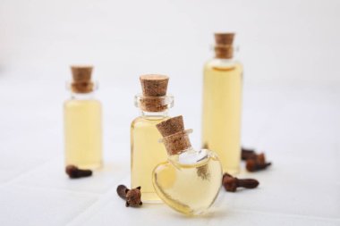 Şişelerdeki karanfil yağı ve beyaz döşemeli masada kurumuş tomurcuklar, yakın plan.