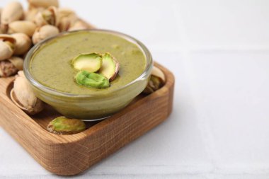 Fıstıklı krema kasede, fındıklı beyaz fayanslı masa, yakın plan. Metin için boşluk