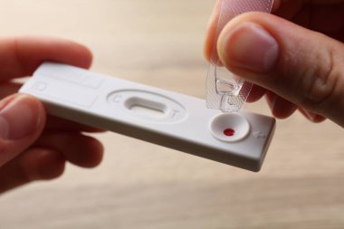 Kadın tampon çözeltisini bulanık arkaplanda tek kullanımlık test kasetine bırakıyor.