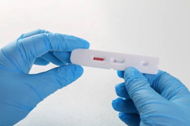 Doktorun elindeki tek kullanımlık Covid-19 ekspres testi beyaz masada, yakın plan.
