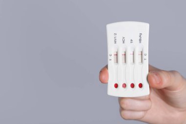 Açık gri arka plan üzerinde tek kullanımlık çoklu enfeksiyonlu ekspres test yapan kadın, yakın plan. Metin için boşluk