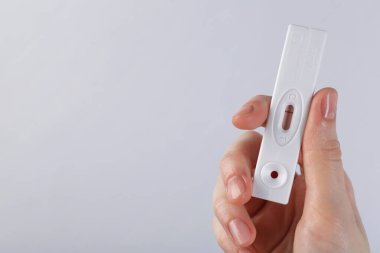 Işıklı arka planda tek kullanımlık ekspres test yapan kadın, yakın plan. Metin için boşluk