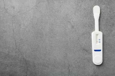 Gri masadaki tek kullanımlık ekspres test, üst görünüm. Metin için boşluk