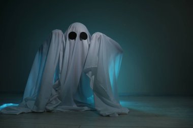Ürkütücü hayalet. Koyu yeşil arkaplan üzerine çarşaf giymiş bir kadın