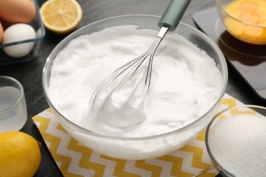 Krem şantili kase, çırpılmış çırpılmış ve malzemeler masada, yakın plan.