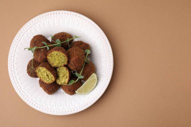 Nefis falafel topları, limon dilimi ve soluk kahverengi arka planda mikro yeşiller, üst manzara. Metin için boşluk