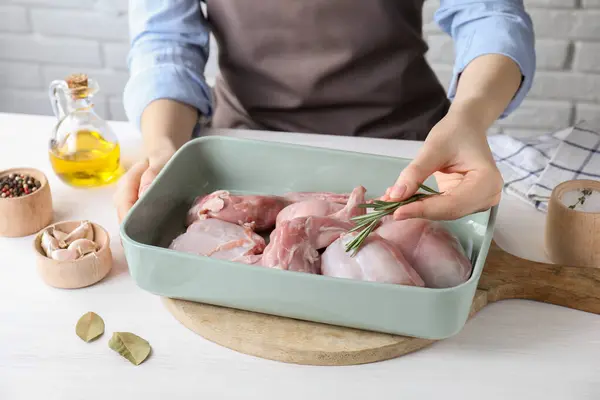 Beyaz ahşap masada çiğ tavşan etiyle biberiye pişiren kadın, yakın plan.