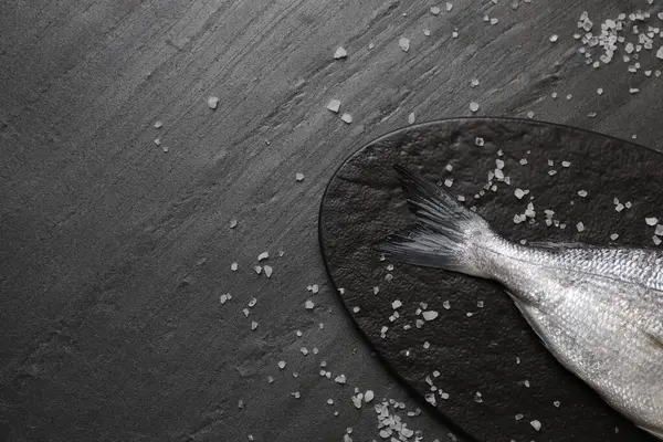 Siyah masada taze çiğ dorado balığı ve deniz tuzu var. Metin için boşluk