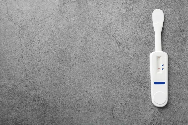 Gri masadaki tek kullanımlık ekspres test, üst görünüm. Metin için boşluk