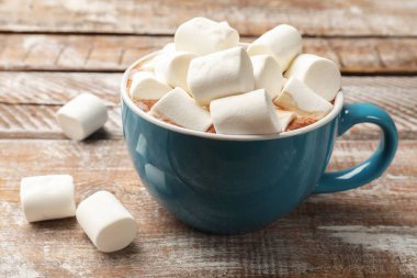 Lezzetli sıcak çikolata, marşmelov ve ahşap masa, yakın plan.