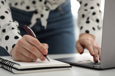 E-öğrenme. Çevrimiçi derste notlar alan bir kadın, kapalı masa, yakın çekim