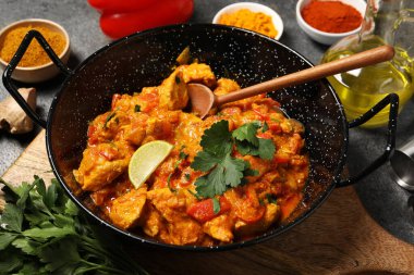 Lezzetli körili tavuk ve gri masadaki malzemeler.