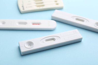 Açık mavi arkaplanda farklı tek kullanımlık ekspres testler