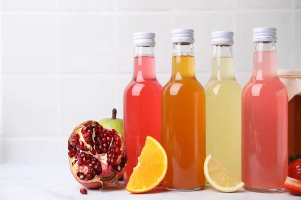 stock image Delicious kombucha in glass bottles and fresh fruits on white marble table