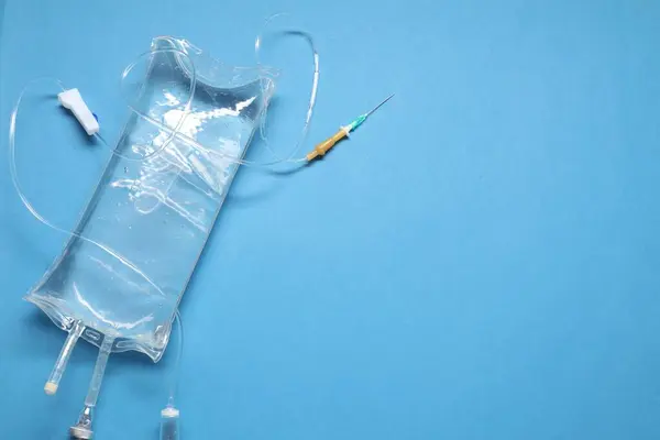 IV infusion set on light blue background, top view. Space for text
