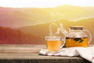 Cam bardakta yeşil çay ve dağlarda ahşap masa üzerinde çaydanlık, metin için yer