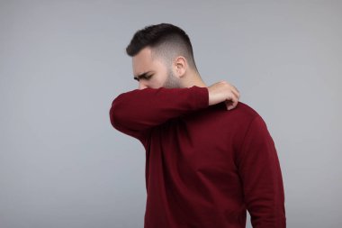 Hasta adam gri arka planda öksürüyor, mesaj için yer var.