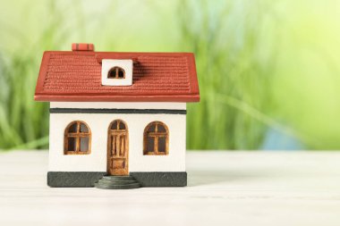 İpotek konsepti. Beyaz ahşap masa üzerinde ev modeli bulanık yeşil arkaplan, metin için boşluk