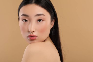 Bej arka planda sağlıklı cilde sahip güzel bir kadın.