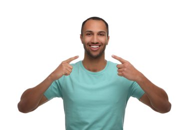 Gülümseyen adam beyaz arka plandaki sağlıklı, temiz dişlerine işaret ediyor.